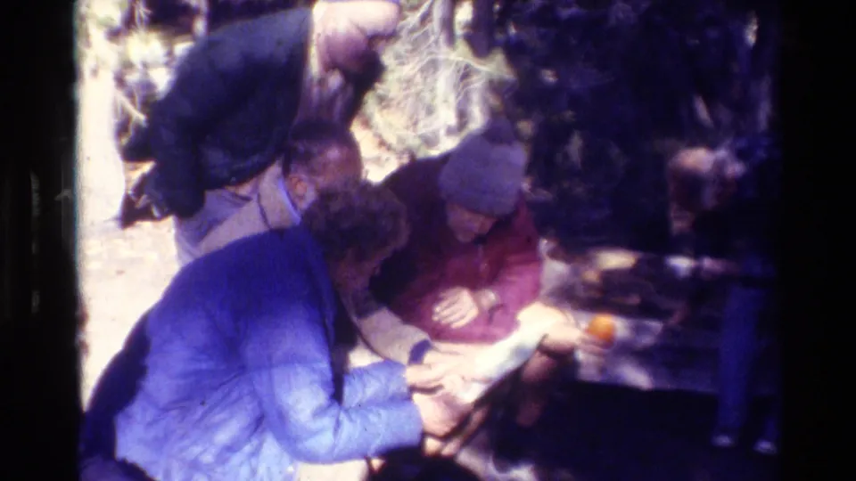 A brief 1981 home-movie frame shows several people gathered closely outdoors, partly obscured by shadow and film blur.