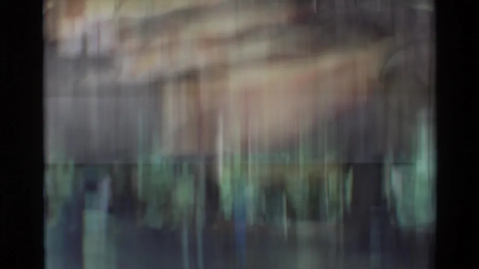 Motion-blurred 8mm transition frame with vertical streaking and soft color bands during a camera move.