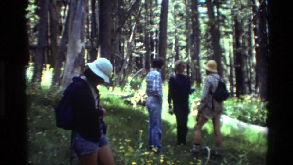 1981 home-movie frame showing a small group of hikers standing in a wooded clearing, listed as British Columbia.