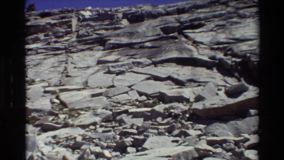 Final 8mm frame of a metadata-labeled British Columbia/USA rocky landscape with fractured slabs and stratified stone ledges.