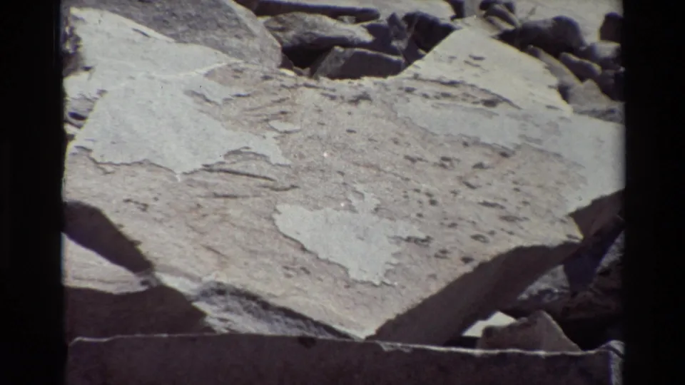 1981 8mm frame showing pale, weathered rock slabs and surrounding darker rubble in the British Columbia location metadata.