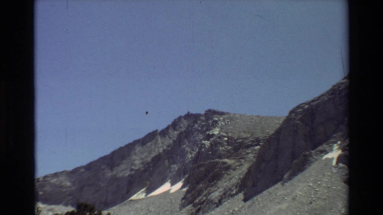 Wide view of a rocky mountain ridge under a clear blue sky.