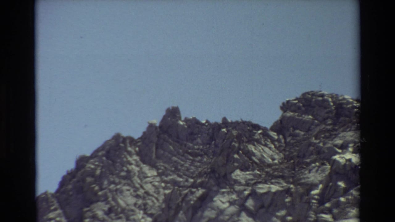 Rocky mountain ridge and pale blue sky in a 1981 8mm home-movie frame from the listed British Columbia location.