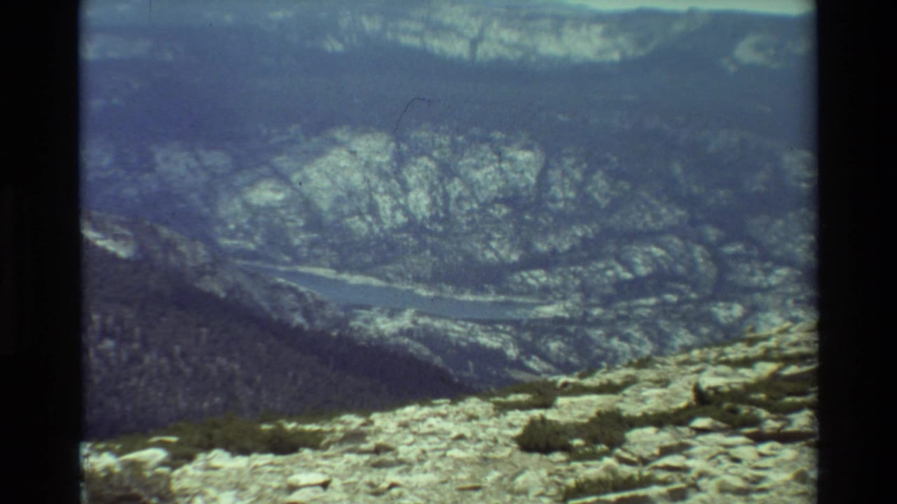 High rocky foreground overlooking forested slopes and a river valley.