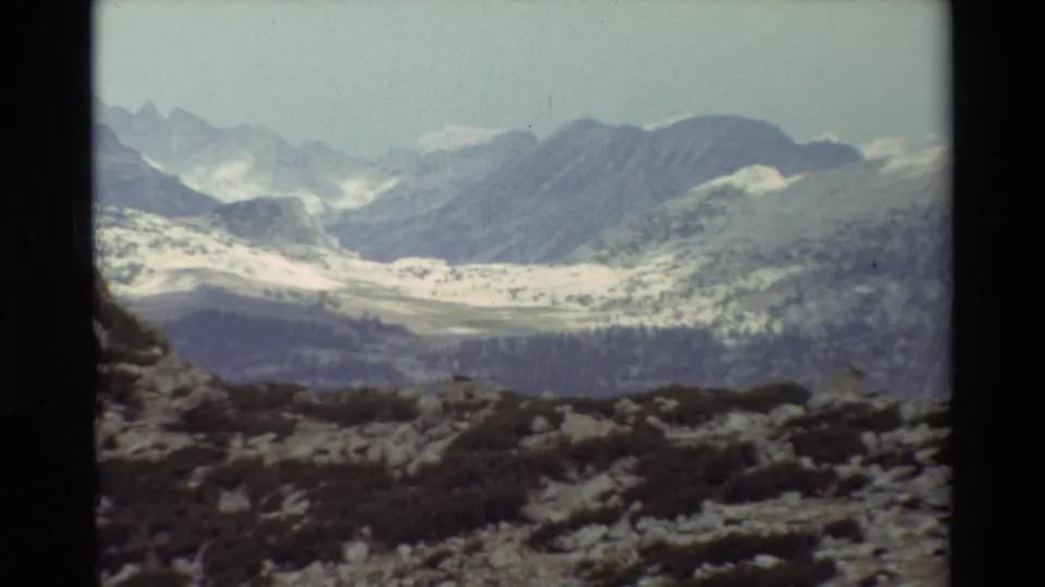 Wide 8mm view of a snow-patched mountain range and rocky alpine ground, consistent with the supplied British Columbia 1981 metadata.