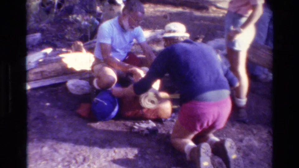Hikers handle camping gear and cookware on the ground in a wooded British Columbia scene from 1981.