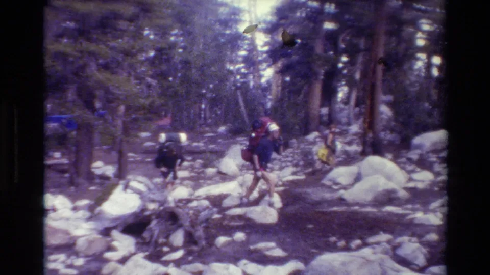 Hikers move through rocky forest terrain in 1981 British Columbia home-movie footage.