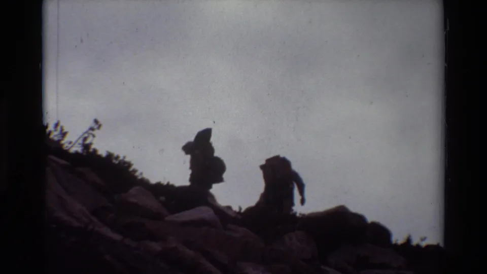 Two hikers with backpacks climb across rocky terrain in archival 8mm footage from the 1981 clip metadata.