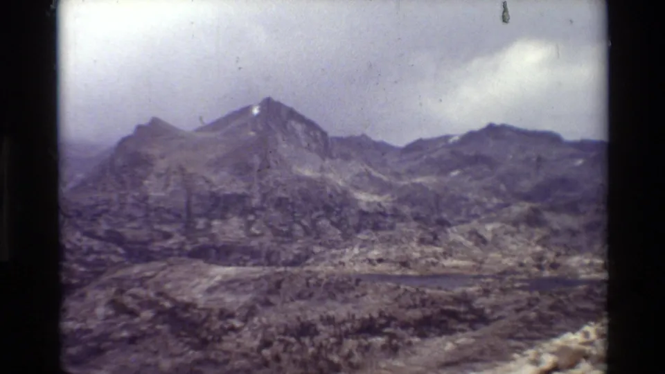 Rugged mountain ridge and small lake appear in a soft, faded 8mm landscape view from the supplied 1981 clip.