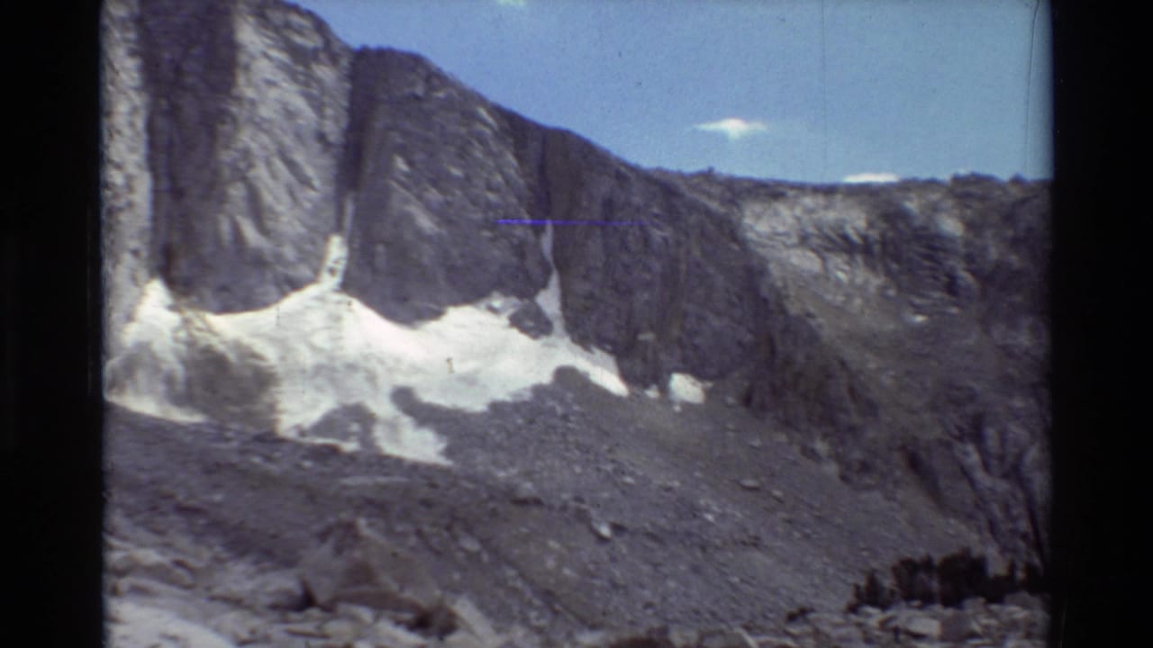 High rock face and snow patches across a barren mountain slope.