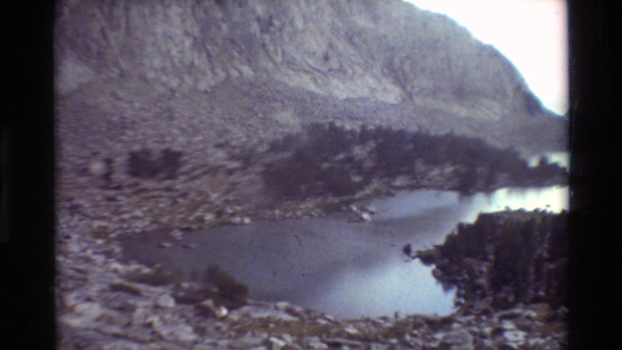 Mountain lake bordered by rocky slopes and dark evergreen shoreline.