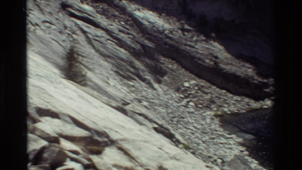 Rocky slope and scree field descending toward a shadowed basin edge.