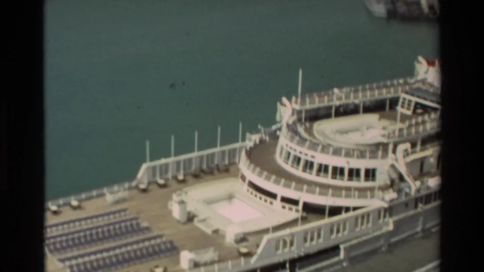 1981 Hawaii frame showing the cruise ship's sun deck, railings, lounge chair rows, and adjacent harbor water.