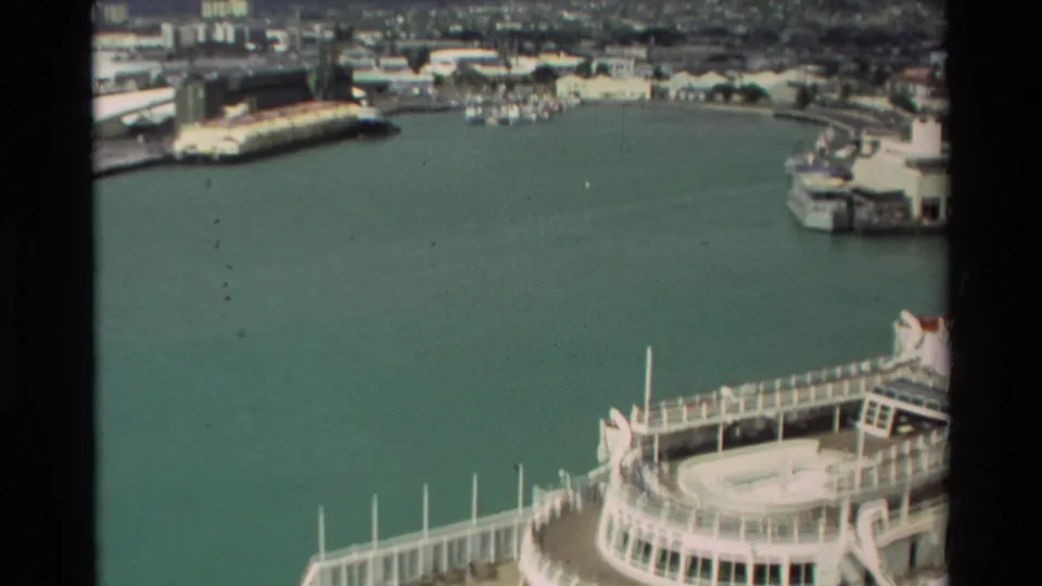 1981 Hawaii home-movie frame with the cruise ship partly in view below a wider harbor and waterfront background.