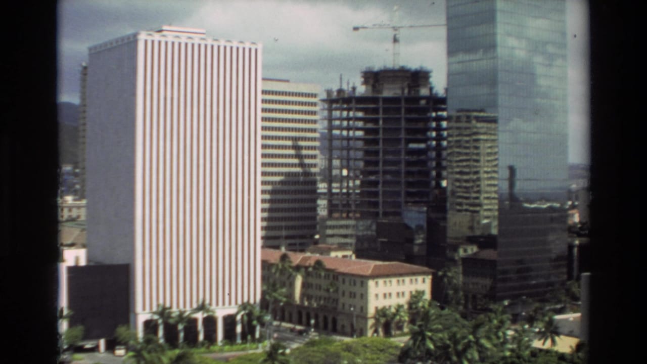 Elevated view of high-rise buildings with palms and a construction crane.