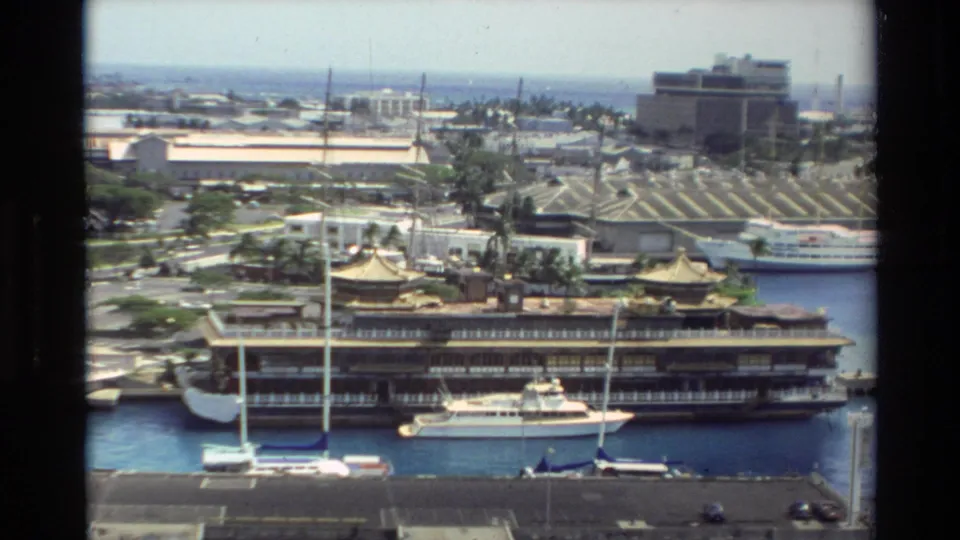 1981 Hawaii marina view with a large docked vessel, yachts, sailboats, and waterfront buildings.