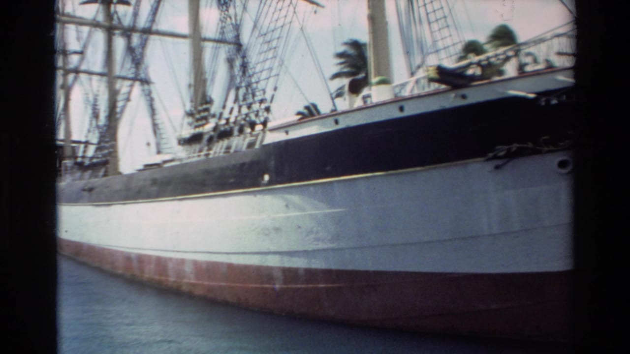 Close view of a docked sailing ship hull with rigging and calm water.