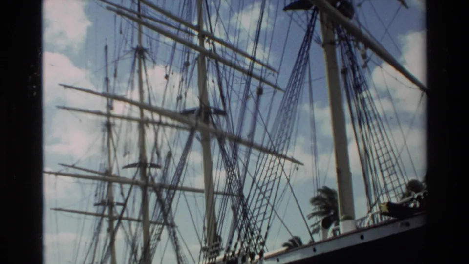 1981 Hawaii home-movie frame focused on the sailing ship's rigging and mast structure, with part of the hull and palm trees visible.