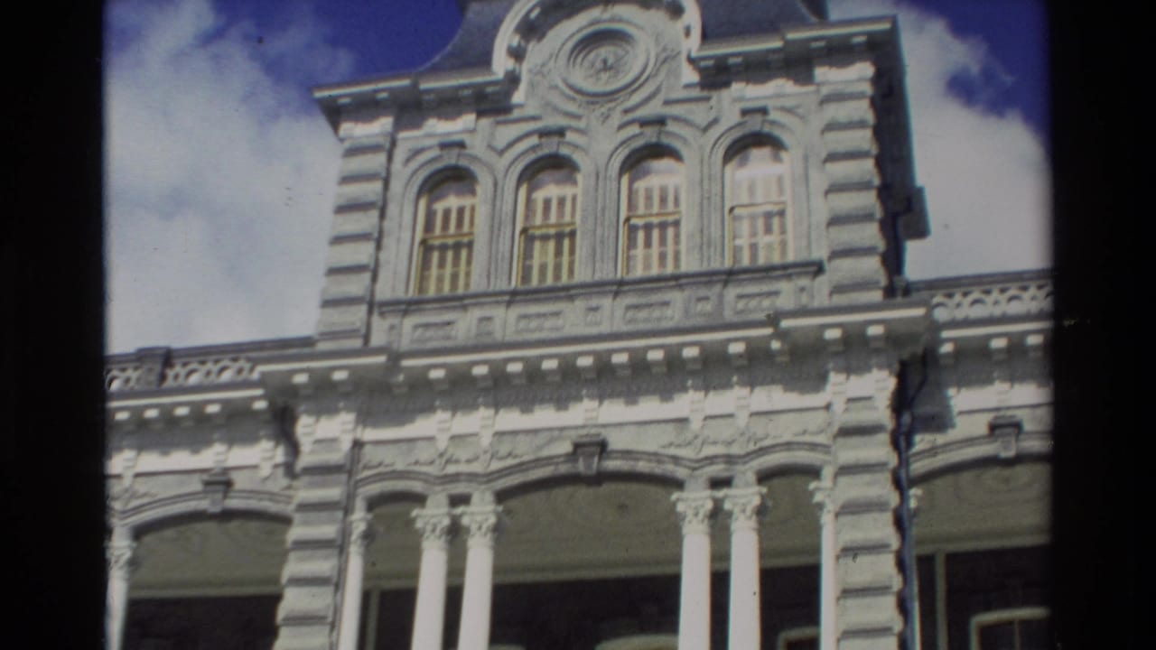 1981 Hawaii home-movie frame showing an ornate white building facade with columns, arched windows, and bright sky.