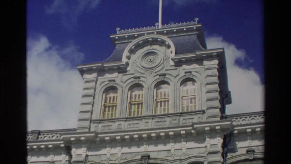 A handheld 1981 Hawaii travel view frames the upper section of a white ornate building against blue sky.