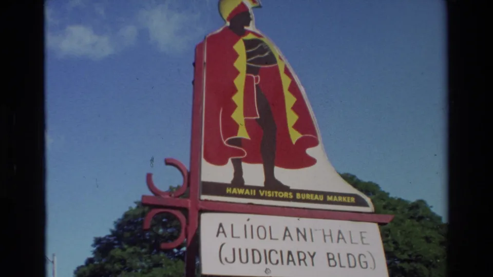 1981 Hawaii frame showing a Hawaii Visitors Bureau marker for Aliiolani Hale, labeled Judiciary Building, against blue sky and trees.