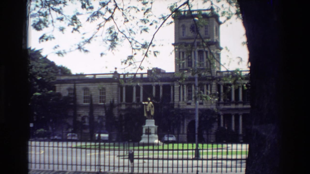 1981 Hawaii home-movie view of King Kamehameha I statue standing before Aliiolani Hale with trees framing the scene.