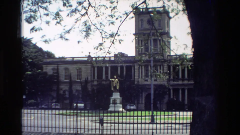 1981 Hawaii home-movie view of King Kamehameha I statue standing before Aliiolani Hale with trees framing the scene.