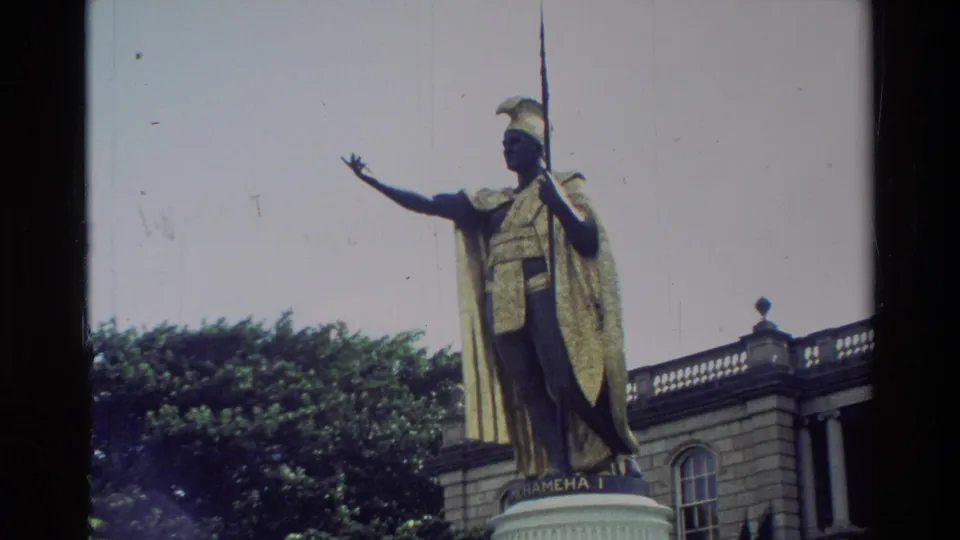 1981 Hawaii 8mm close view of the King Kamehameha I statue with spear and cape, backed by trees and Aliiolani Hale details.