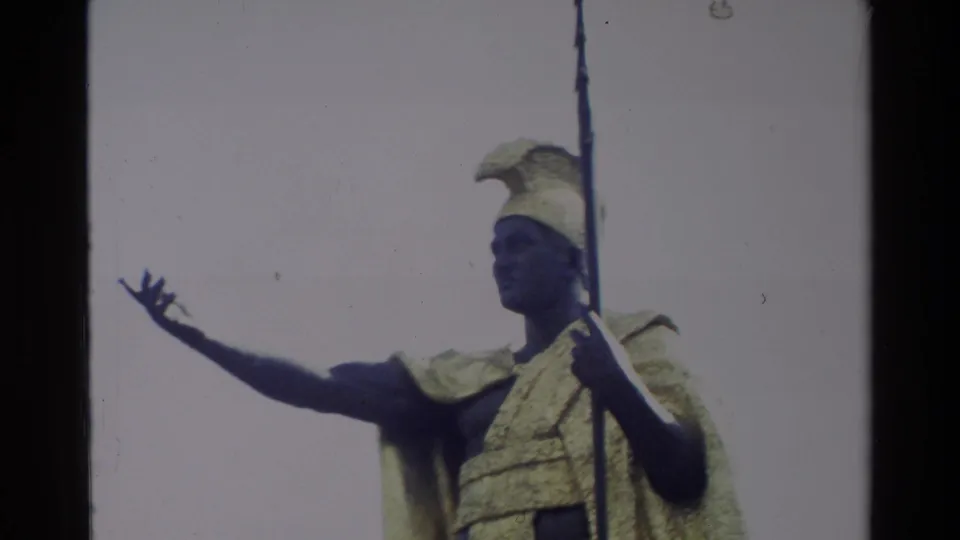 Final 1981 Hawaii frame showing the King Kamehameha I statue in close view, with spear, golden cloak, helmet, and pale sky.