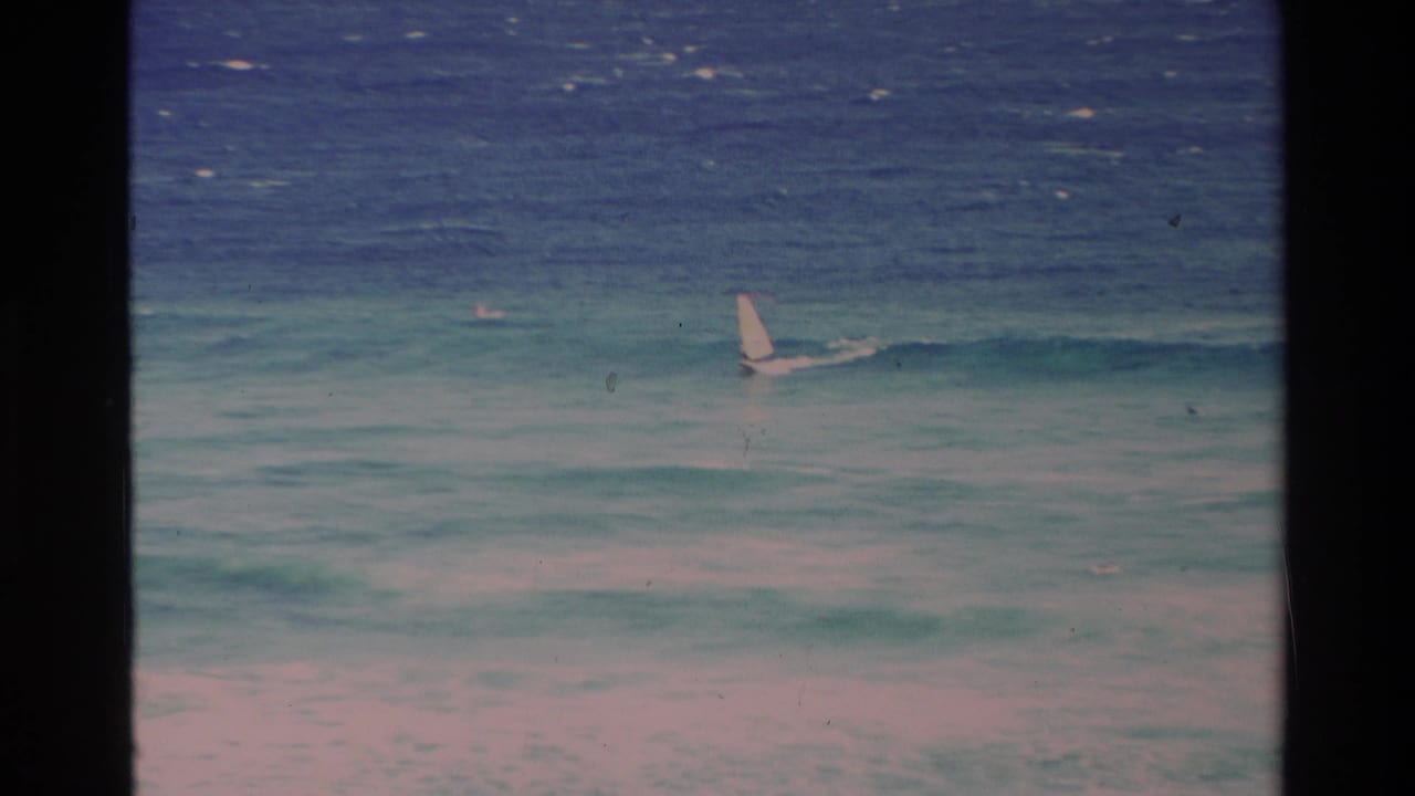 Small white sail offshore on turquoise waves with dark 8mm frame borders.