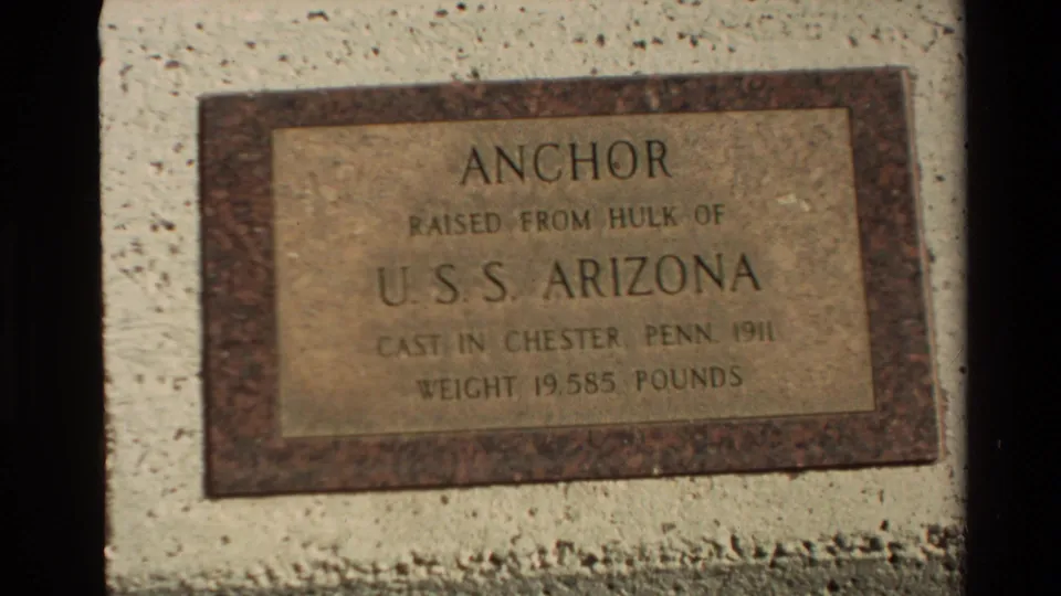 Handheld 8mm close-up of the USS Arizona anchor plaque, with the memorial inscription filling most of the frame.