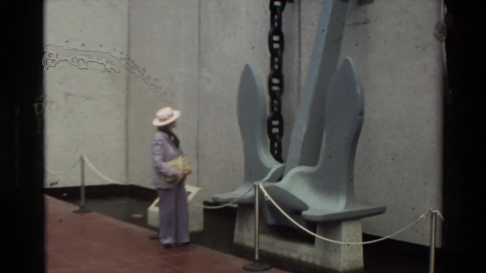 1981 Hawaii home-movie frame showing a visitor near the USS Arizona anchor display at Pearl Harbor.