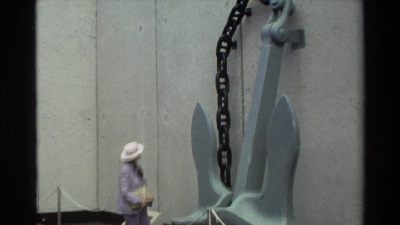 Closer view of a woman walking past the gray anchor and heavy chain display.
