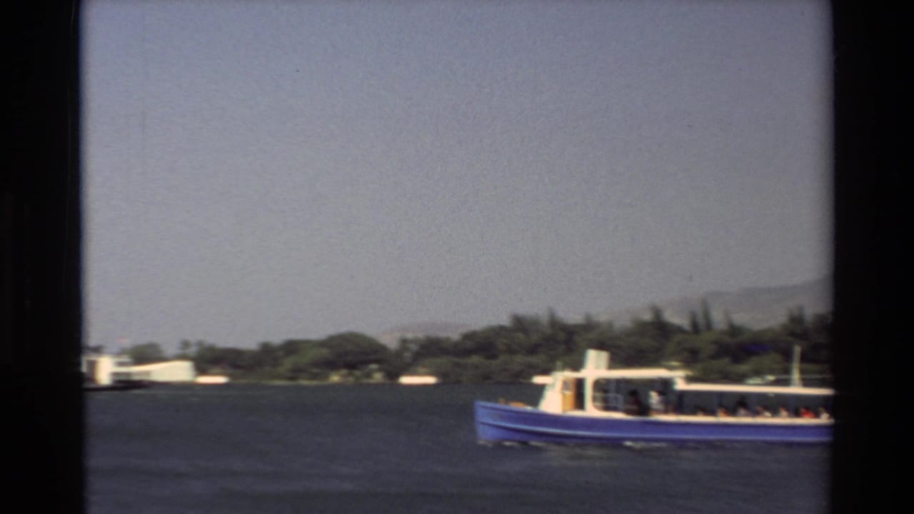 Blue passenger boat crossing dark water with green shoreline and hills in the distance.