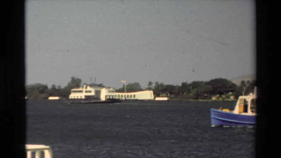 1981 Hawaii 8mm frame showing a white ferry near shore with part of a blue passenger boat in the foreground.