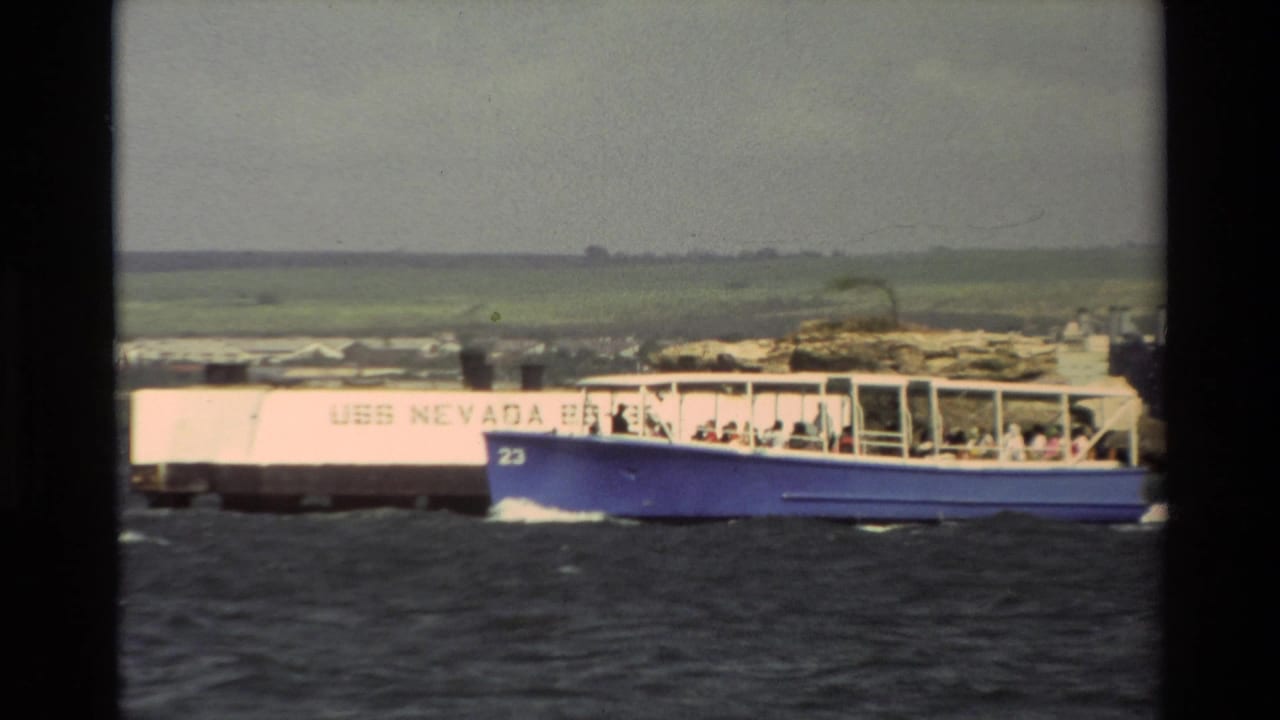 1981 Hawaii home-movie frame showing a passenger tour boat moving across harbor water near the memorial area.