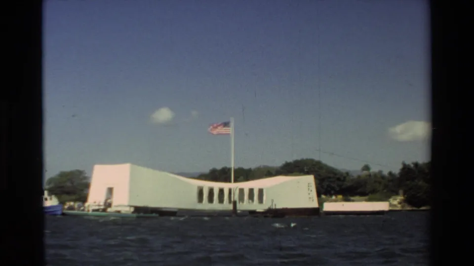 1981 Hawaii 8mm frame showing the memorial exterior from offshore, with the American flag visible against the sky.