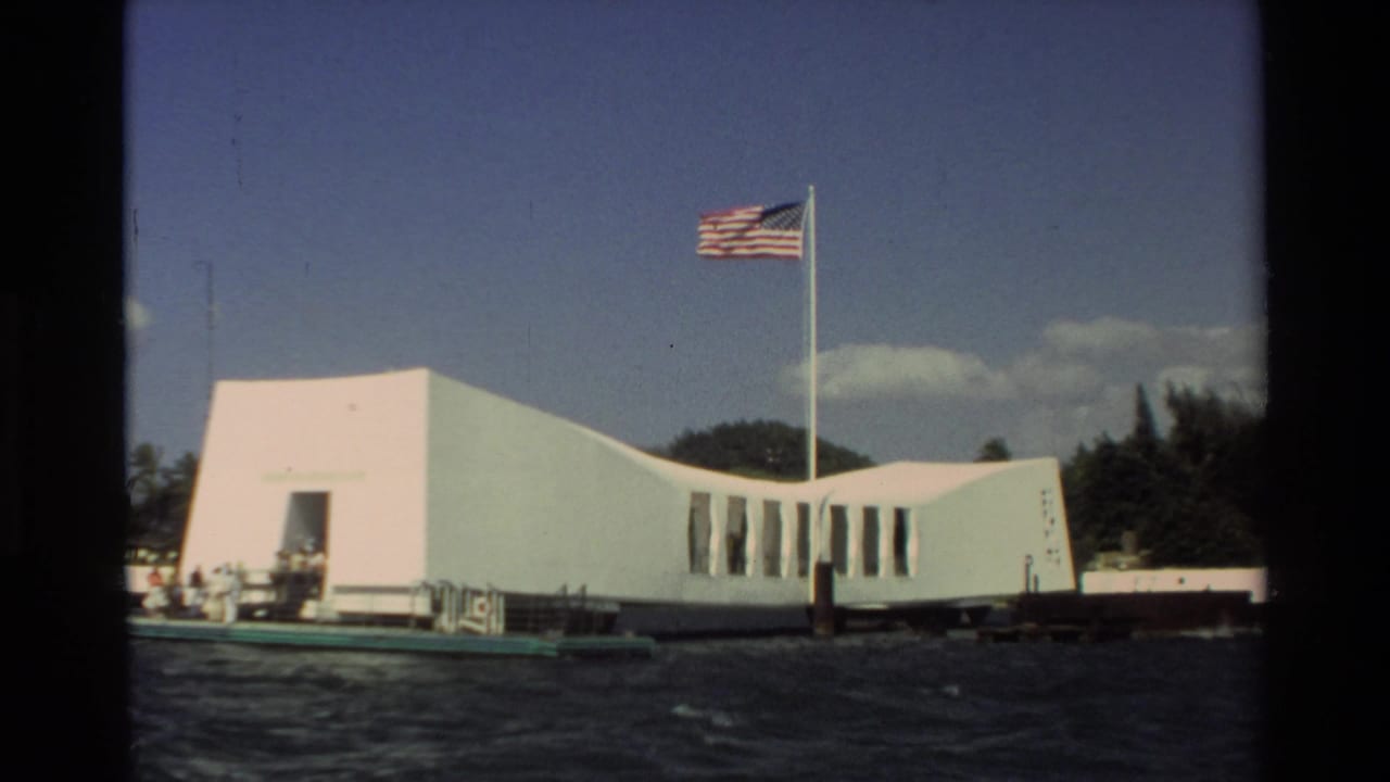 USS Arizona Memorial on water with an American flag flying above it.