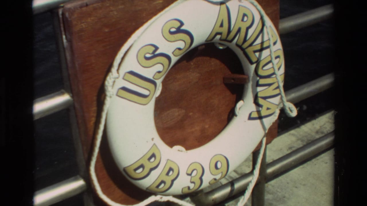 White USS Arizona BB 39 life ring mounted on wood beside metal railings.