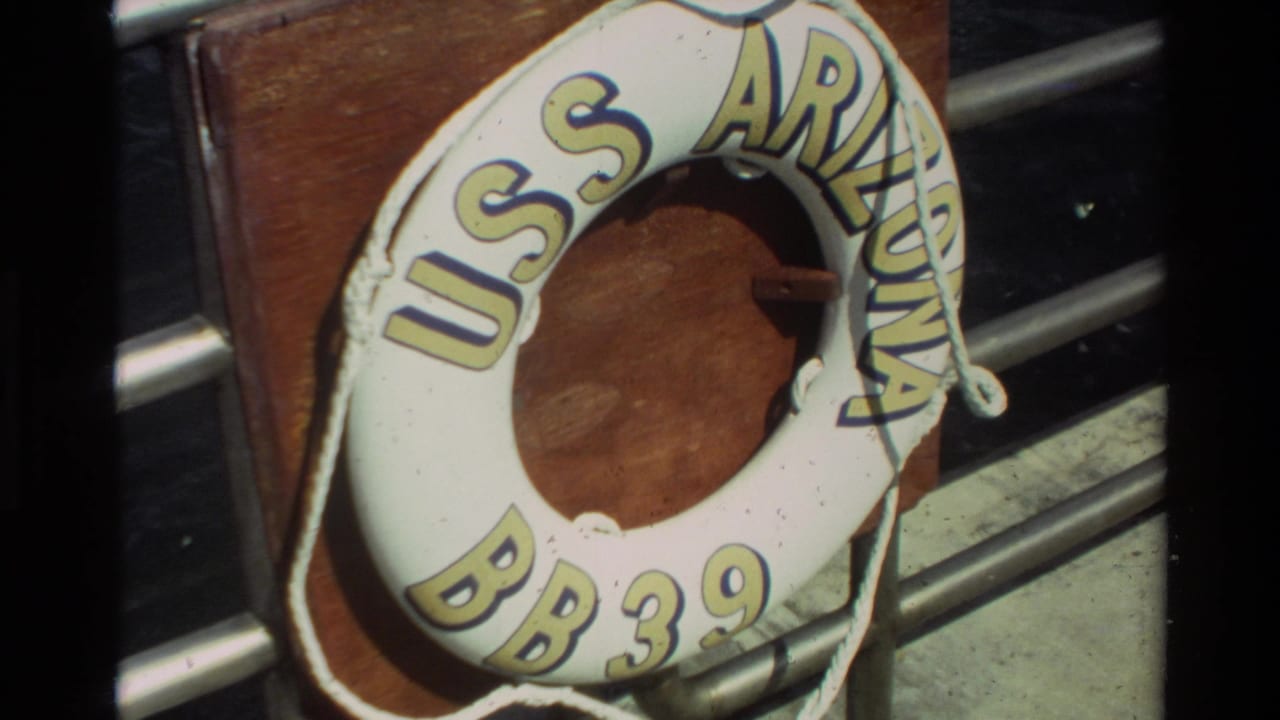 Second close 8mm frame of the USS Arizona BB 39 life ring, with rope, wood backing, and railings in view.