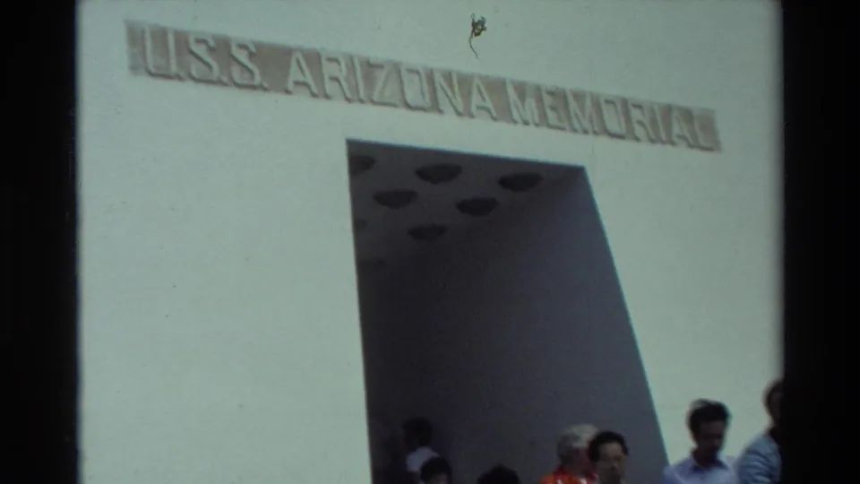 1981 Hawaii 8mm frame showing the USS Arizona Memorial inscription above the entrance with several visitors below.