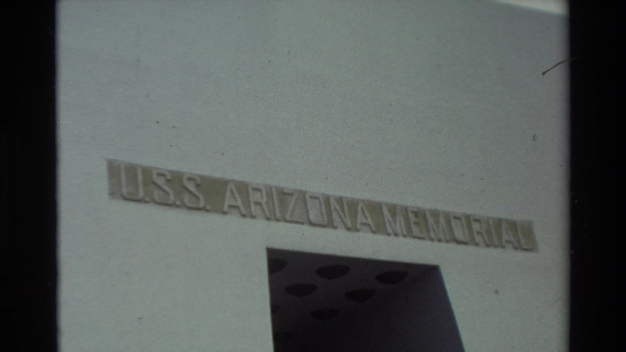 USS Arizona Memorial lettering on a white facade beside a dark architectural opening.