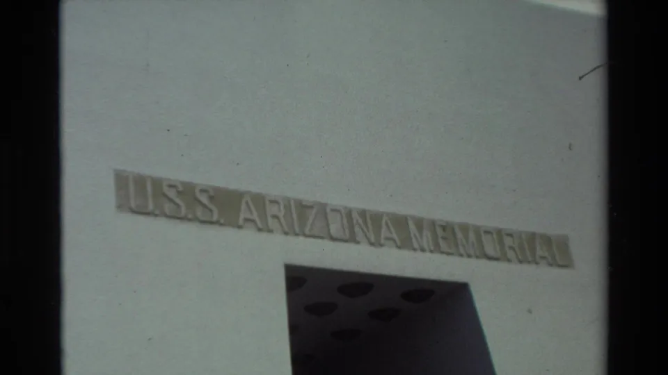 1981 Hawaii 8mm frame showing the USS Arizona Memorial name on a white exterior wall with a dark geometric opening below.