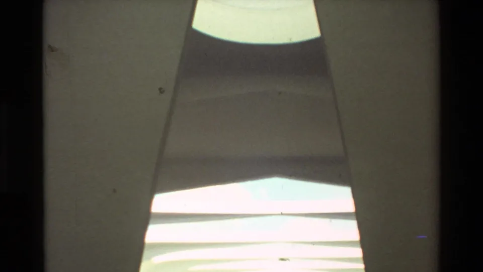 1981 Hawaii 8mm frame looking through the USS Arizona Memorial architecture toward bright ceiling bands and a narrow opening.