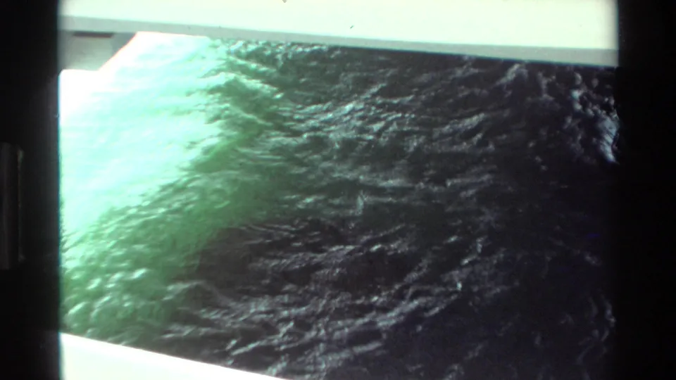 1981 Hawaii 8mm frame showing turbulent green water near a pale dock or boat edge, with heavy film borders and soft exposure.
