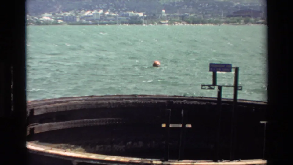 1981 Hawaii 8mm view across the platform edge toward open water, an orange buoy, and a soft distant shoreline.