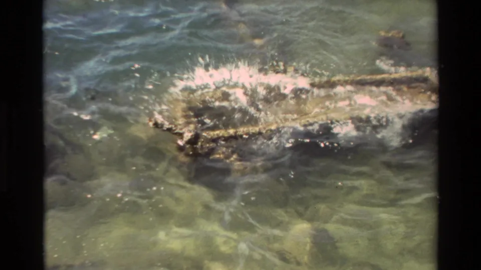 1981 Hawaii 8mm frame showing a close splash in harbor water as a net or line appears to move through the surface.