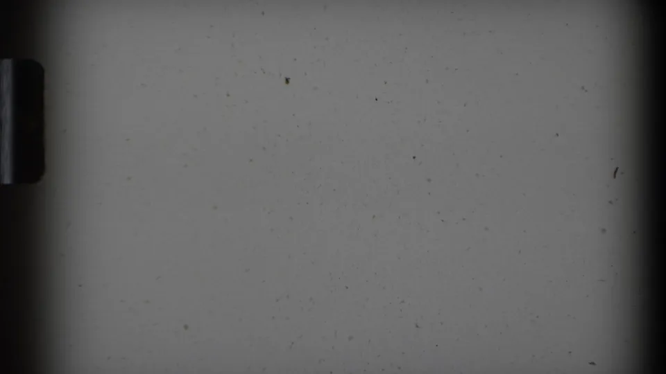 Scanned 8mm frame with dark film borders, a gray exposed field, and scattered dust or debris marks.