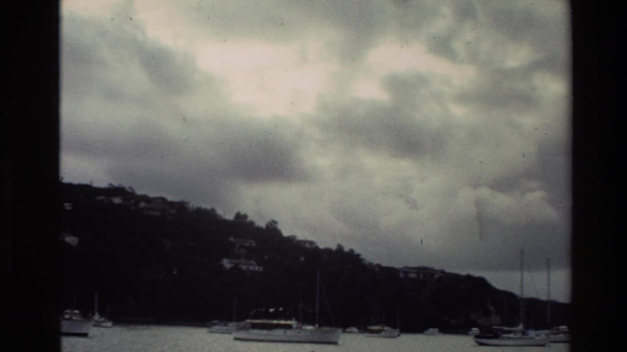 Anchored boats and hillside shoreline seen through a dark film frame divider.