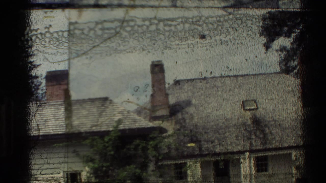 1981 New Zealand home-movie frame with a partially obscured building exterior, roofline, chimneys, and heavy film-edge marks.